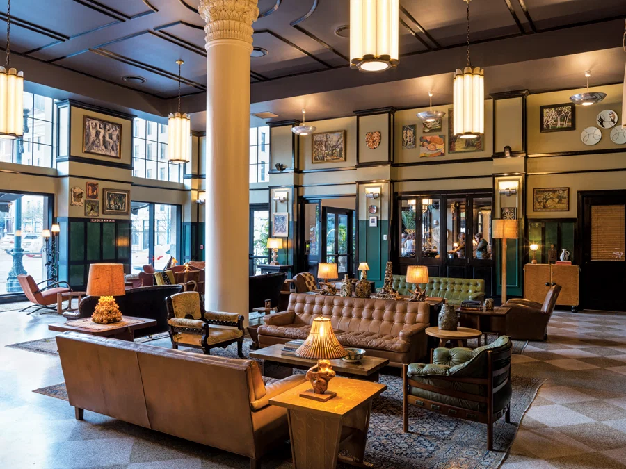 Long communal tables and a piano in a tall hotel lobby